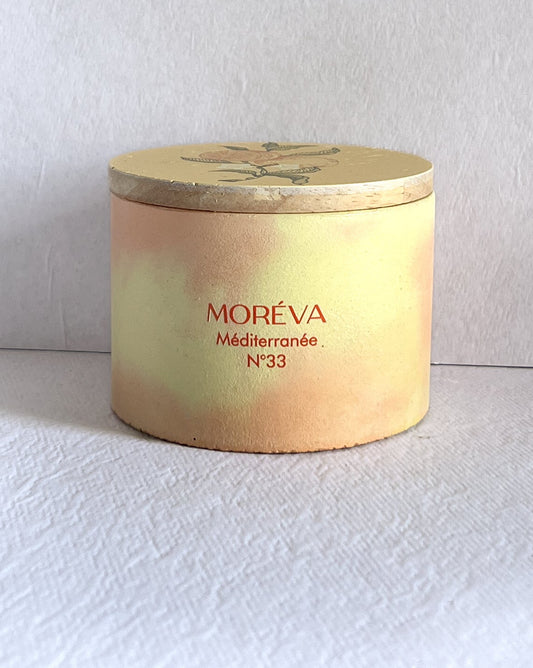 an orange and citrus fragrance candle in a concrete jar